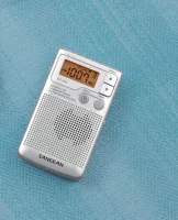 Sangean DT-250 cep radyosu avuç içi boyutunu gösteren kumaş zeminde
